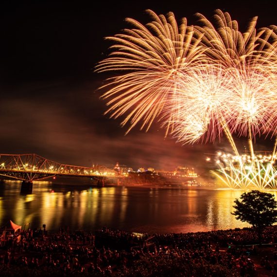 Feux d’artifice rouge, orange et jaune à côté du pont Alexandra la nuit.