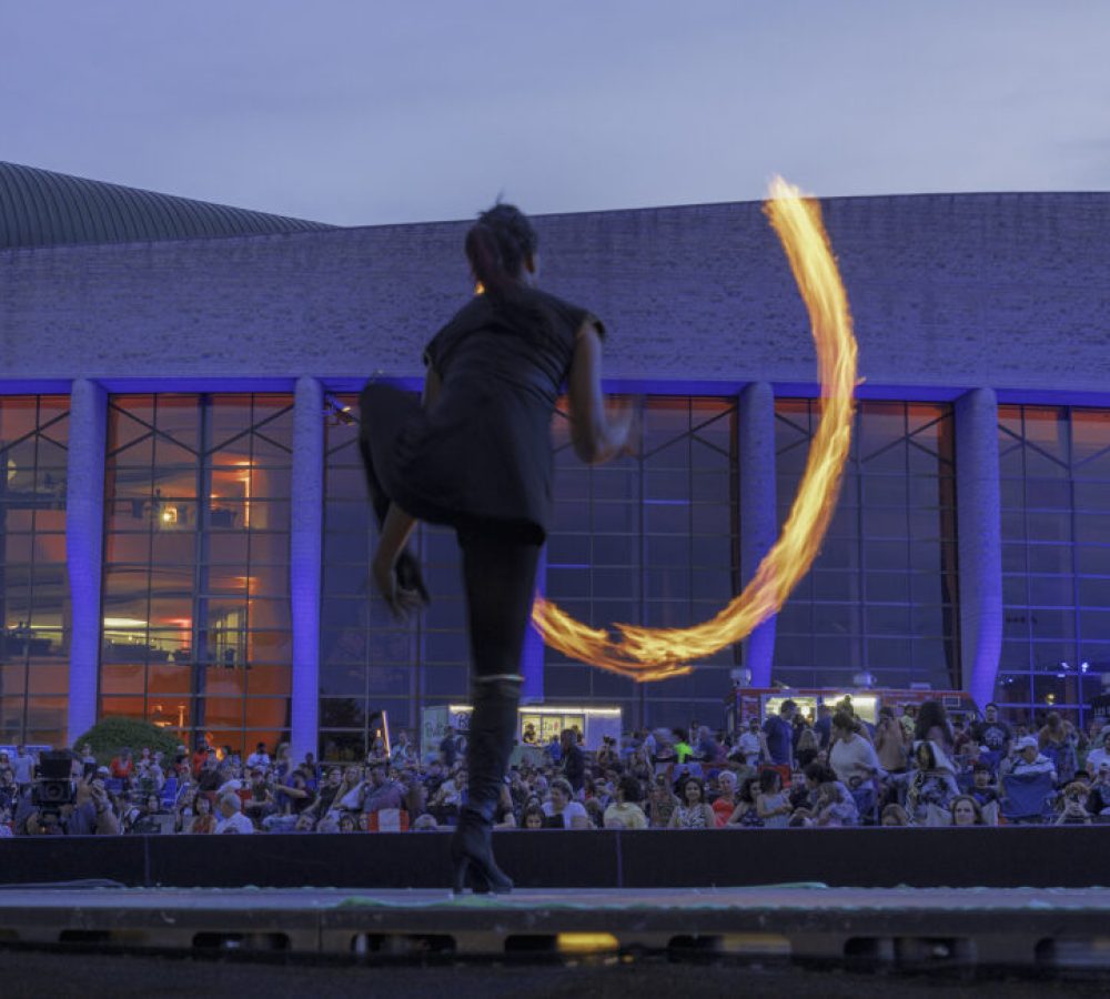 Artiste qui fait une prestation avec du feu devant une foule.
